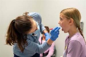 Nurse doing a strep test on a small girl patient. 